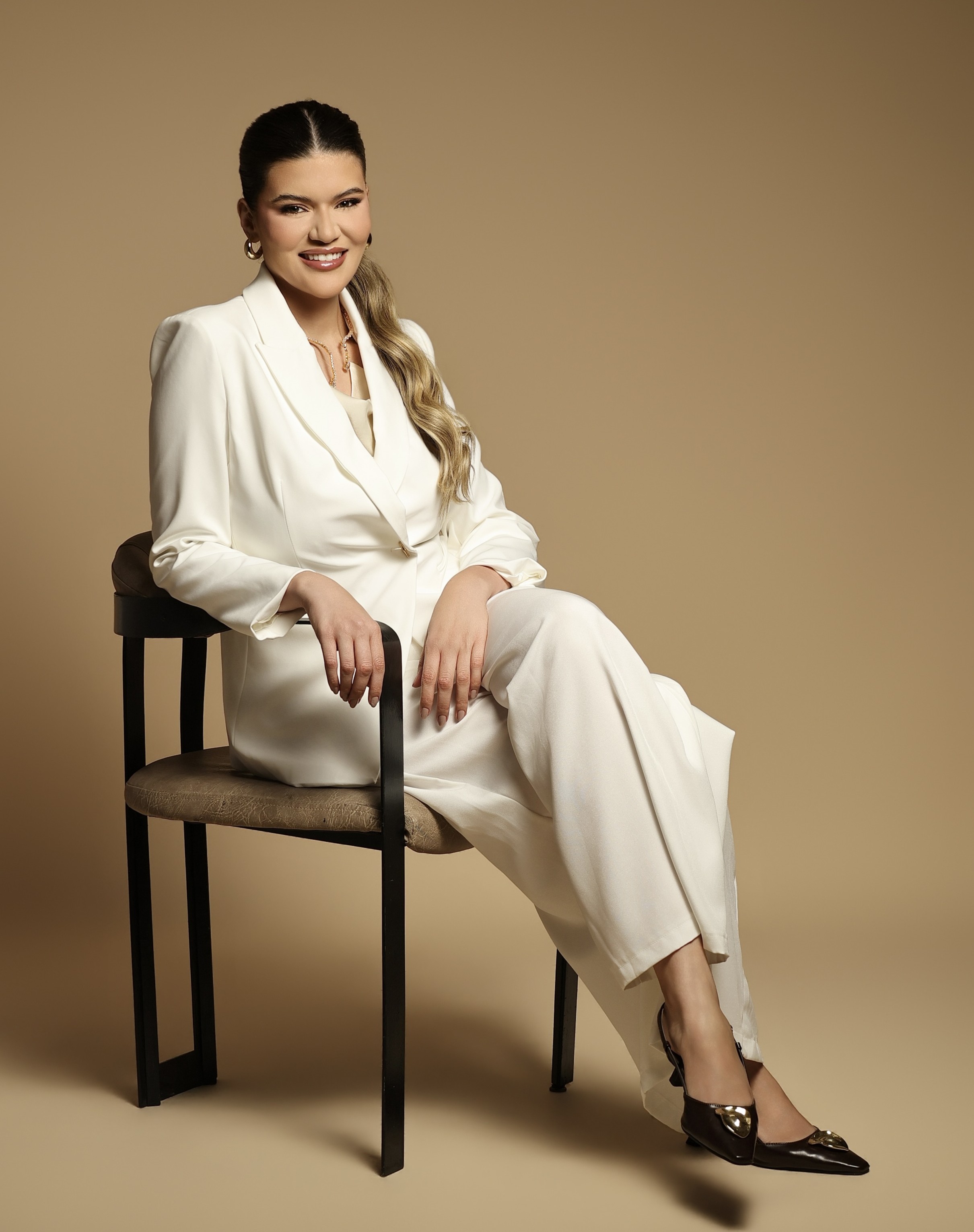 Dra. Viviane Iocca sentada em uma cadeira, usando conjunto branco